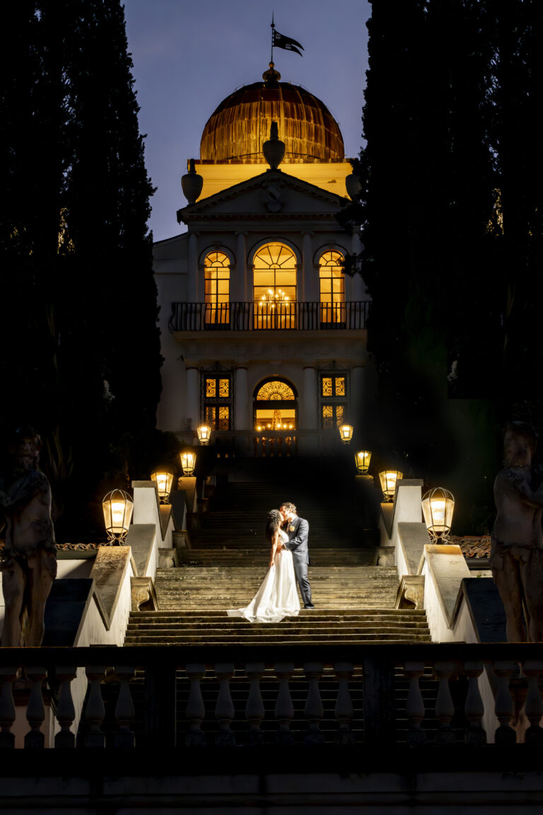 A couple kissing on the floodlit steps of a domed villa at night, Stefano Lunardi