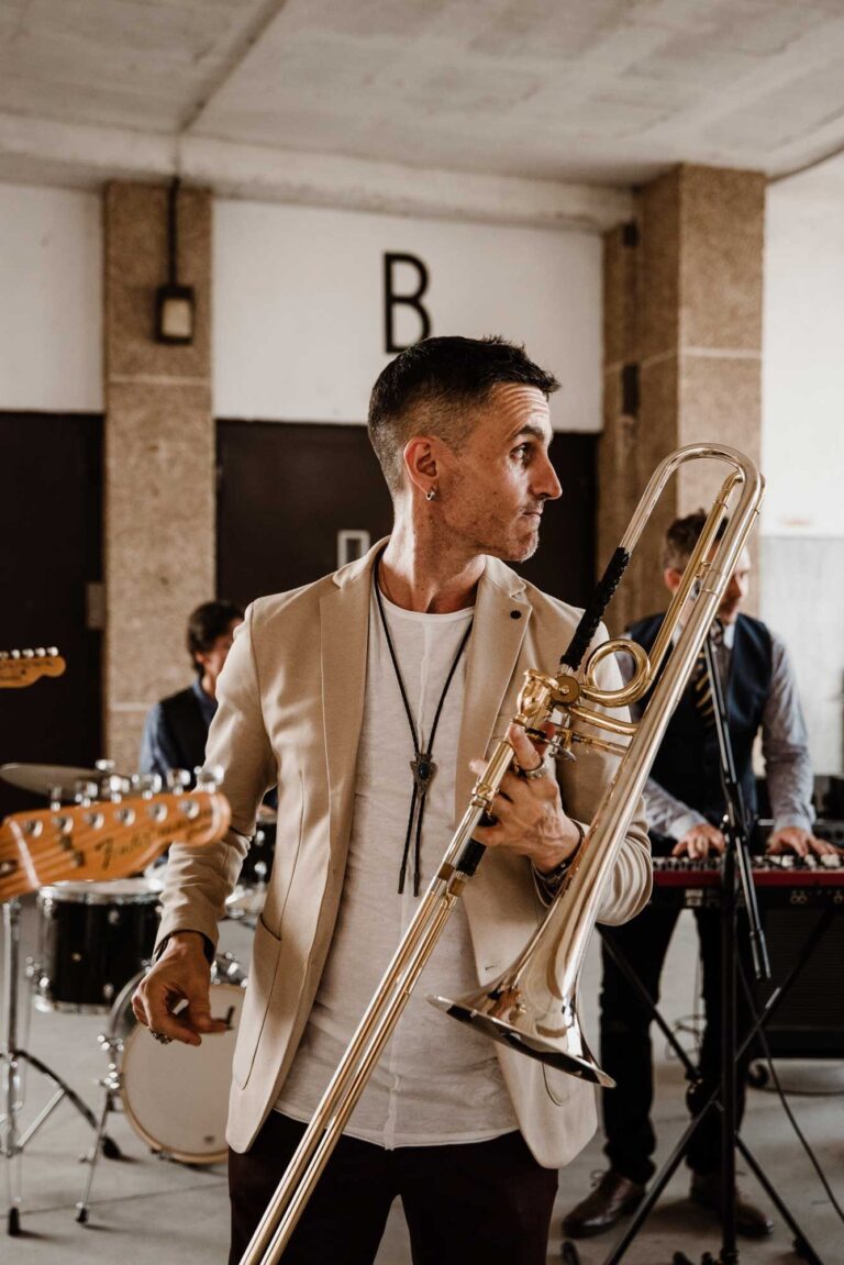 A trombonist in a cream jacket playing with the band behind him, Stereo Star Band