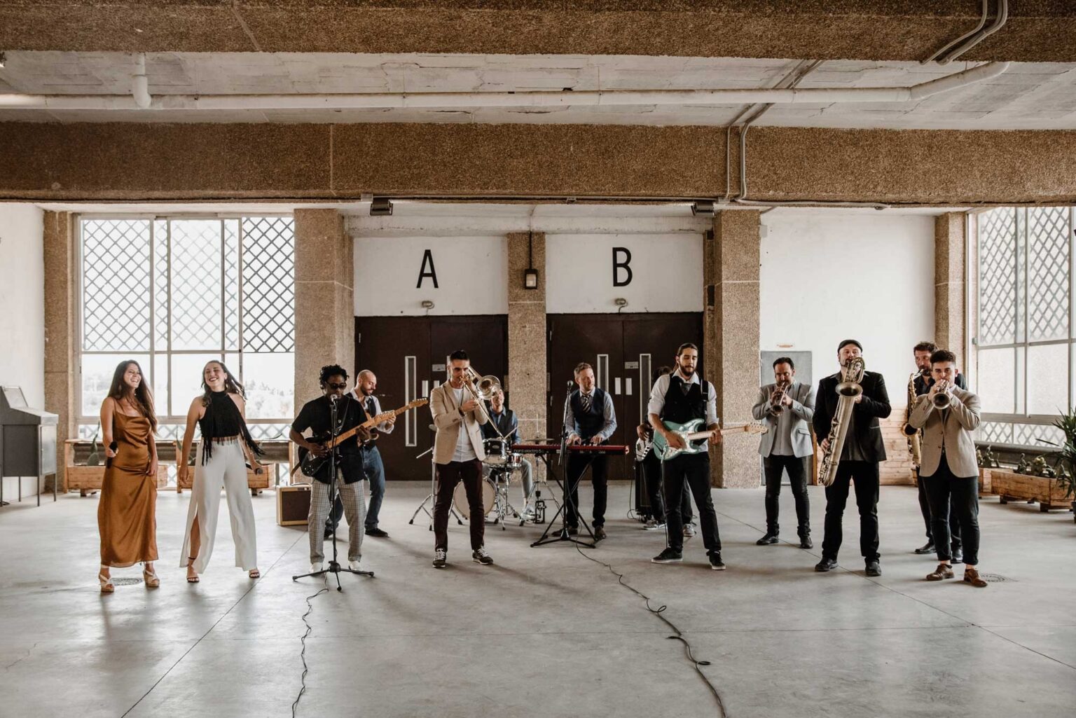 The band set up and performing in a large concrete hall with tall windows