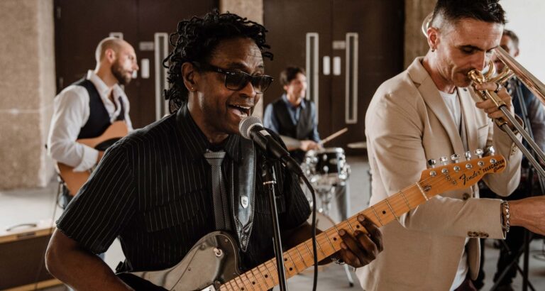 A guitarist and singer in the foreground with a trombonist beside him, Stereo Star Band
