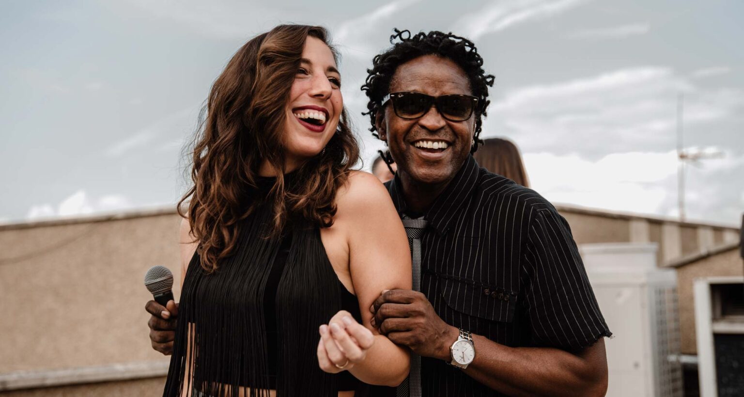 A female singer and a male singer laughing together on stage