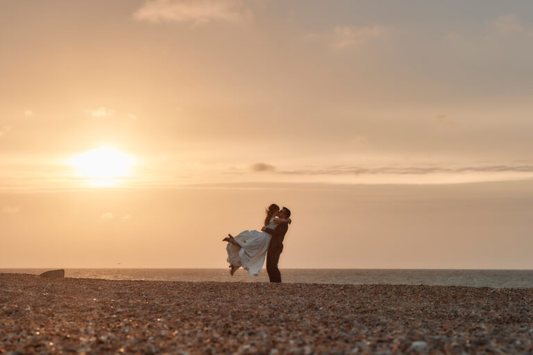 A groom lifting his bride on the beach at sunset, Barn Drift wedding, Stuart Wood Photography