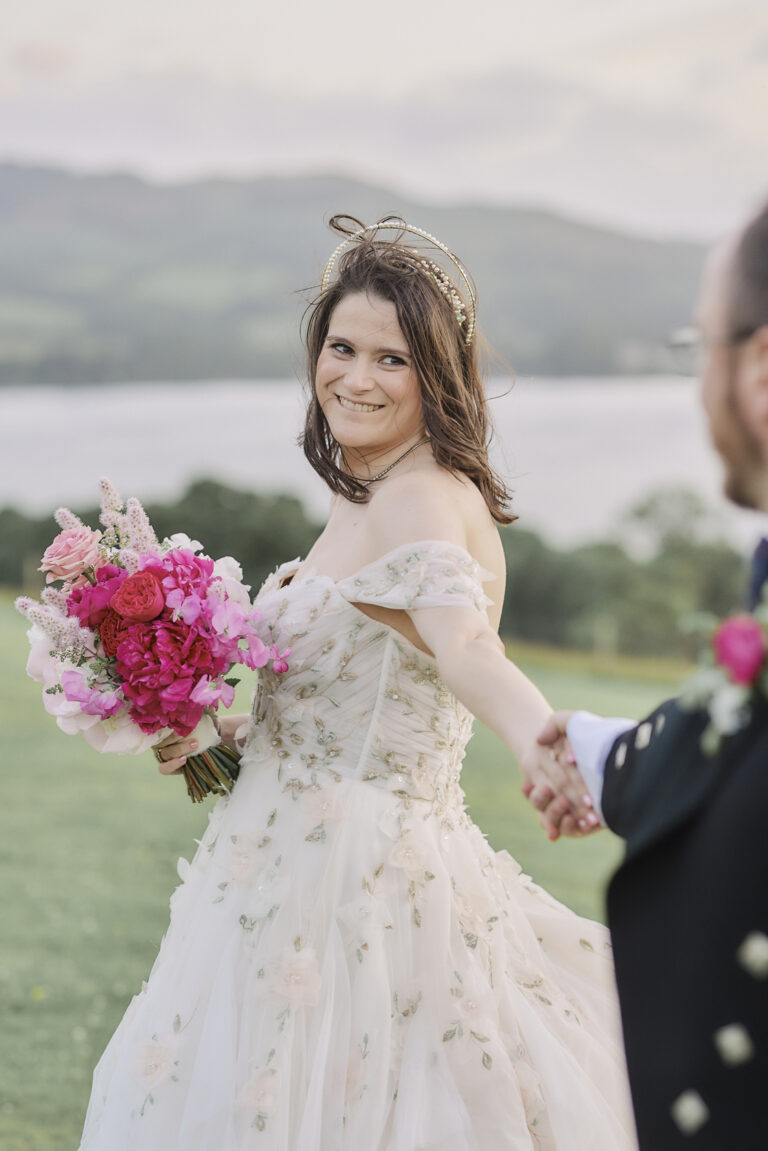 A bride leading her groom by the hand, Loch Lomond behind her, Stuart Wood Photography