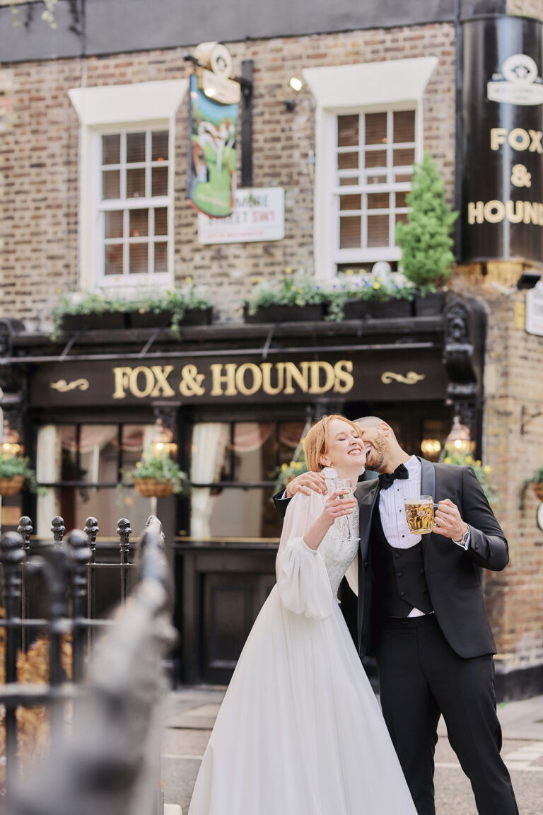 A bride and groom raising a toast outside the Fox and Hounds pub in London, Stuart Wood Photography