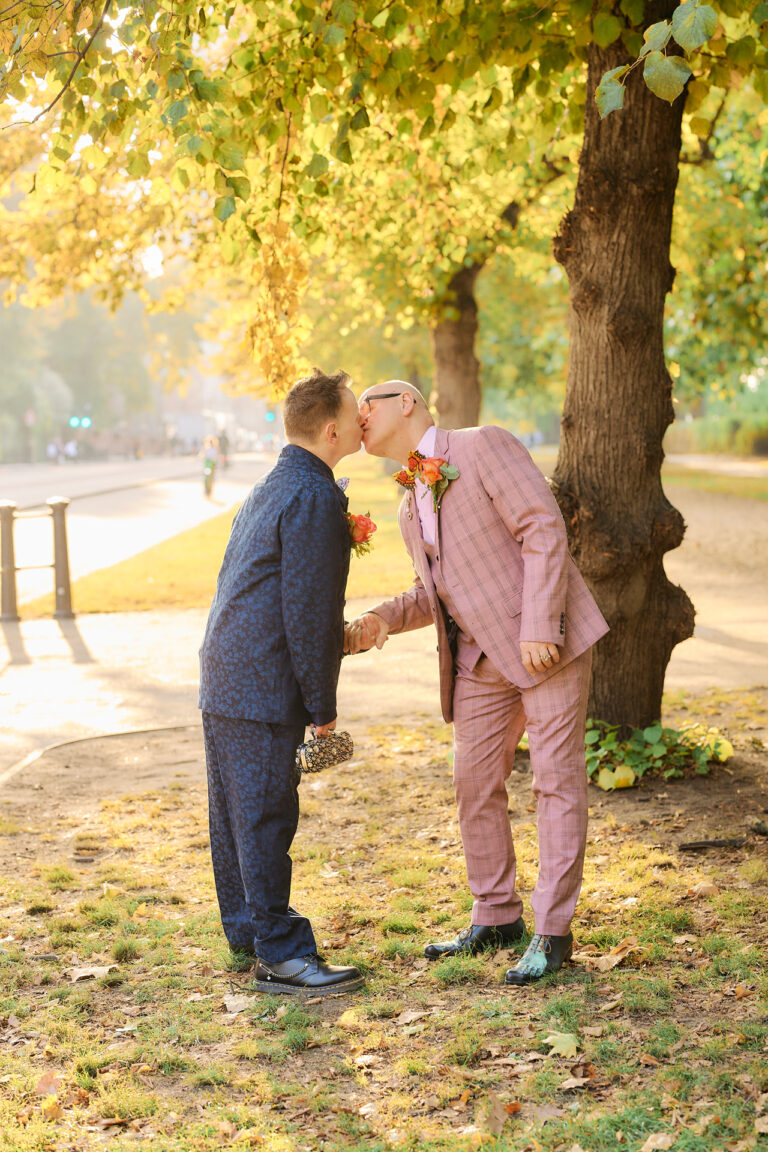 Two grooms sharing a kiss under autumn trees, a Mandarin Oriental wedding in London, Stuart Wood Photography