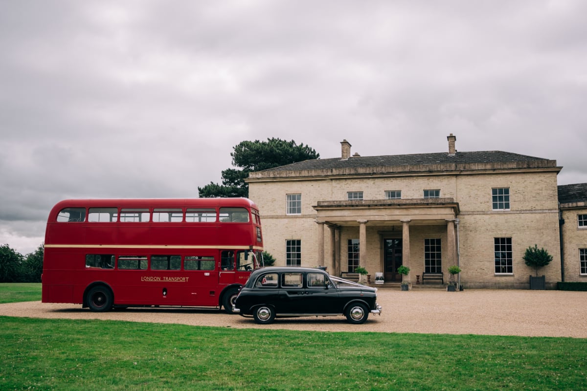 A red double-decker bus and a black London taxi in front of the portico of Stubton Hall