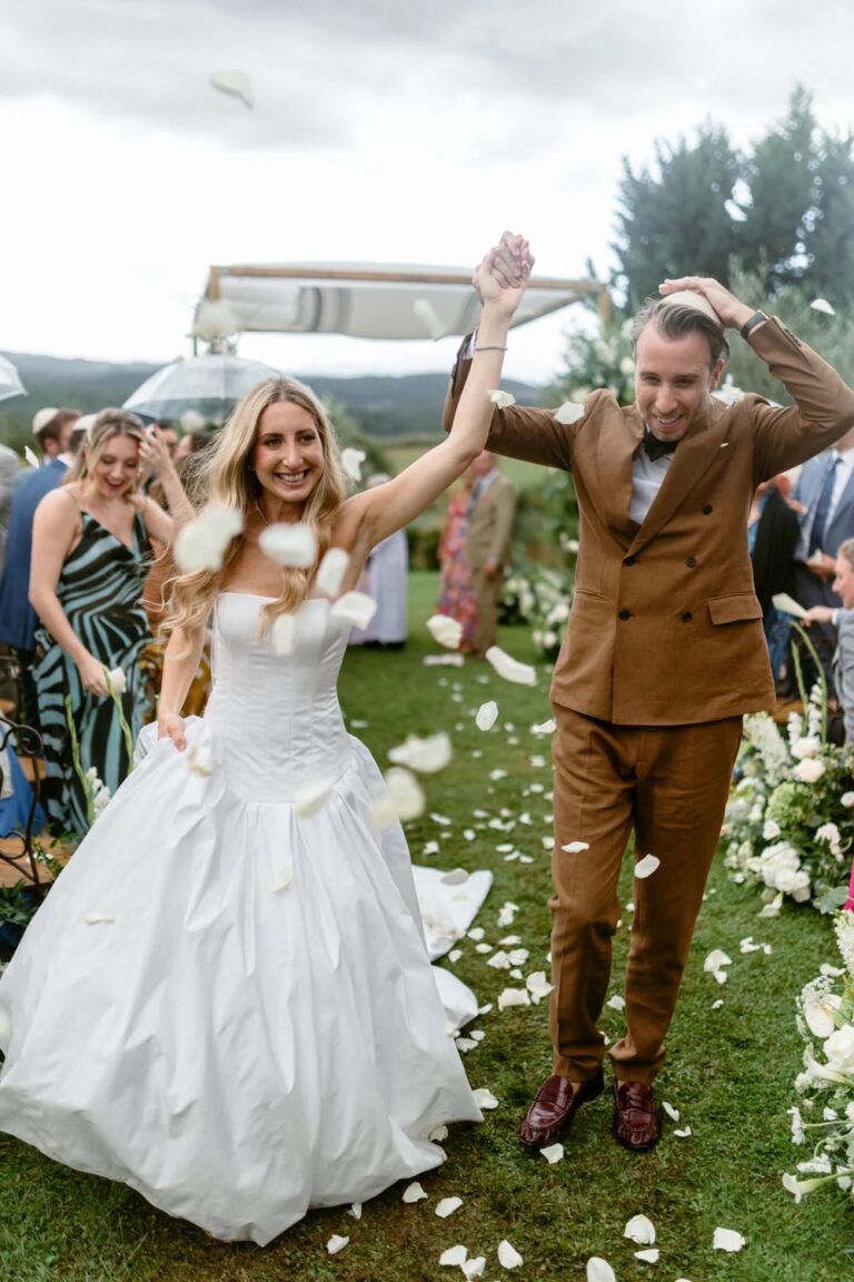 The couple walking back up the aisle through falling petals after their ceremony at Borgo Casabianca, Tuscany, Studio Fotografico Bacci