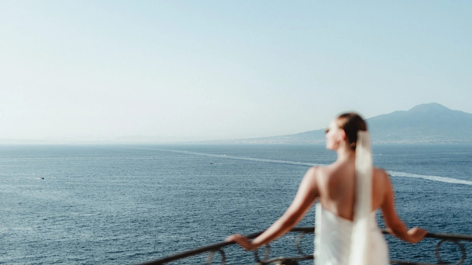 A bride on a balcony above the Bay of Naples, with Vesuvius across the water, Sorrento, Studio Fotografico Bacci