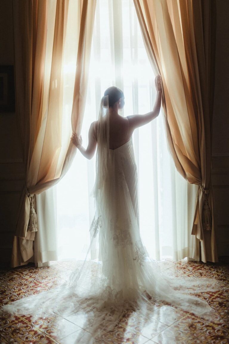 A bride at a curtained window at the Grand Hotel Excelsior Vittoria, Sorrento, Studio Fotografico Bacci