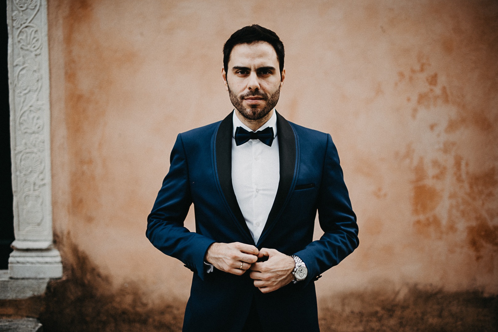 The groom, alone, against ochre stone, Studio27 by Andreas Politis Photography and Cinematography