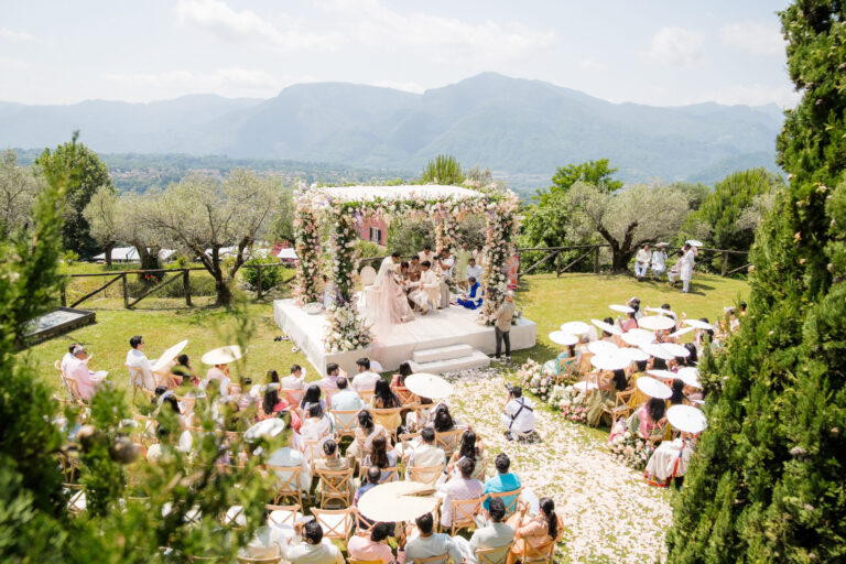 A South Asian wedding ceremony under a flowered mandap on a garden lawn, hills behind, Suellen Fernandes Weddings & Celebrations