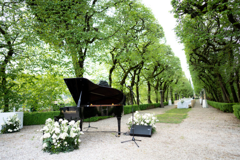A grand piano set on the gravel at the head of a tree-lined avenue, Verona, Suellen Fernandes Weddings & Celebrations