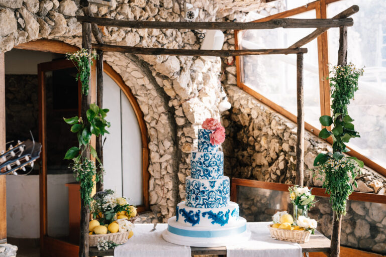 A tiered cake painted in blue and white maiolica under a pergola on the Amalfi Coast, Suellen Fernandes Weddings & Celebrations