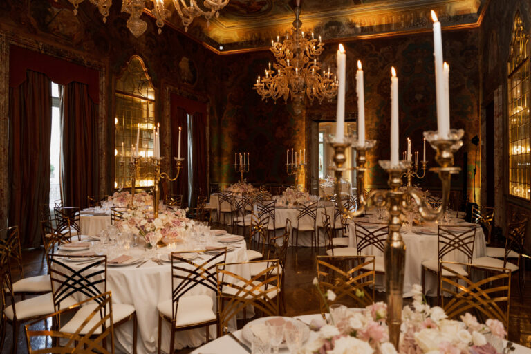 A gilded, mirrored ballroom laid for dinner with silver candelabra, tall candles and blush flowers, Suellen Fernandes Weddings & Celebrations