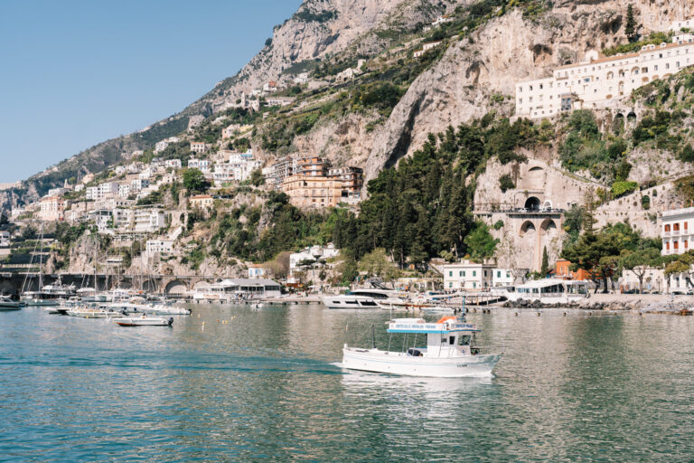 Amalfi seen from the water, the town stacked up its valley, boats on the bay, Suellen Fernandes Weddings & Celebrations