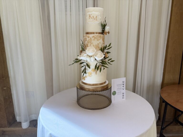 A white tiered cake with gold detail and sugar flowers, Sugar and Spiced Cakes