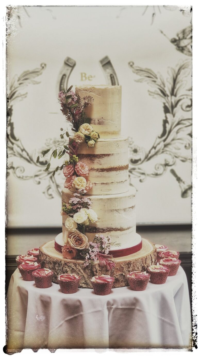 A tiered cake with sugar flowers and a table of cupcakes, Sugar and Spiced Cakes