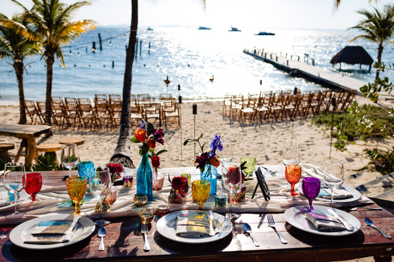 Beachfront reception table set with colourful glassware, SunHorse Weddings