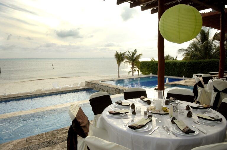 Round reception table set beside a pool and the sea, Isla Mujeres, SunHorse Weddings