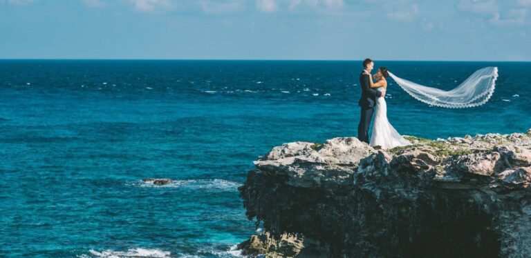 Couple on a rocky headland above the Caribbean, veil in the wind, Isla Mujeres, SunHorse Weddings