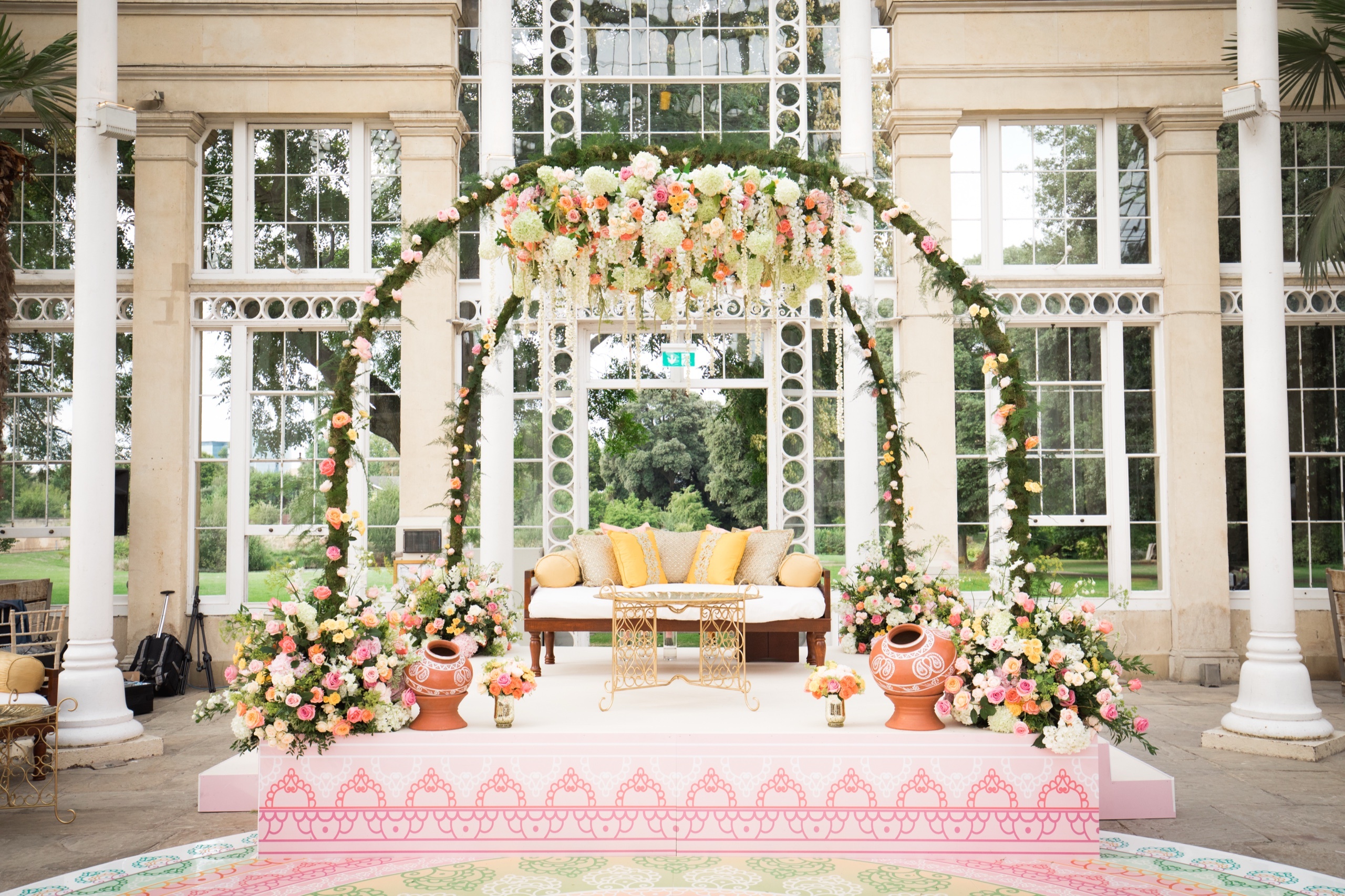 A floral mandap beneath the glazed dome of the Great Conservatory, set for a ceremony, Syon Park