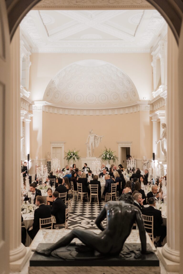 The Great Hall dinner glimpsed through an archway, a bronze figure in the foreground, Syon Park