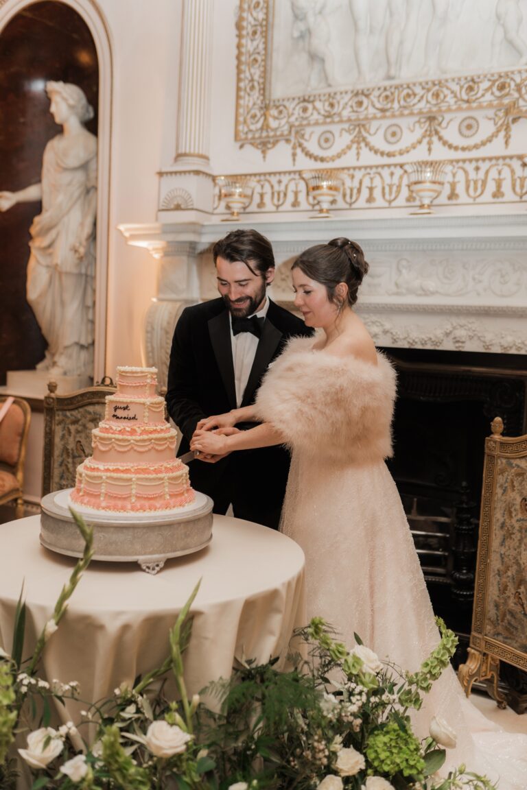 Cutting a tiered cake beside a marble chimneypiece and a classical statue, Syon Park