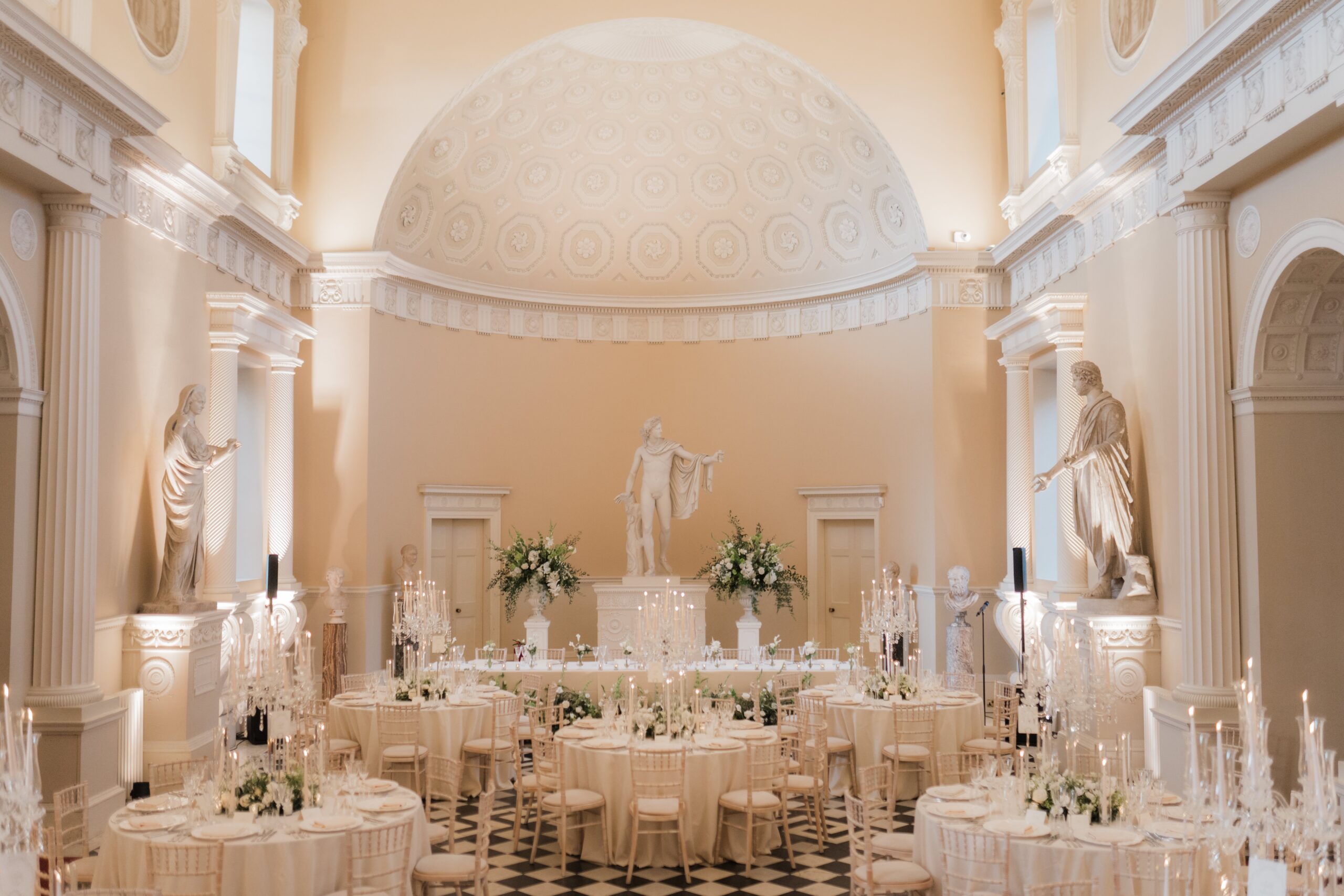 The Great Hall laid for a wedding breakfast, round tables beneath Robert Adam's coffered half-dome and a marble Apollo, Syon Park