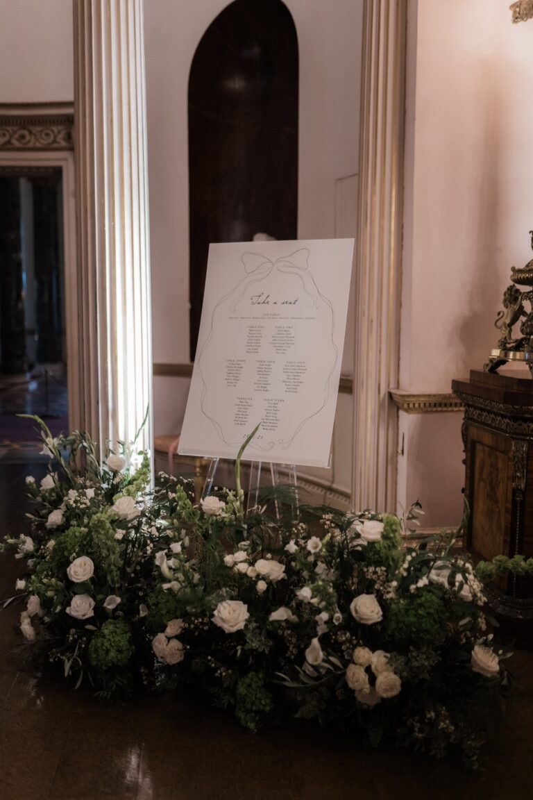 The table plan set on an easel and framed by low white roses between the columns, Syon Park