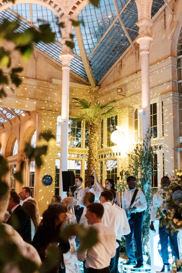 Guests dancing beneath the palms in the lit Great Conservatory at night, Syon Park