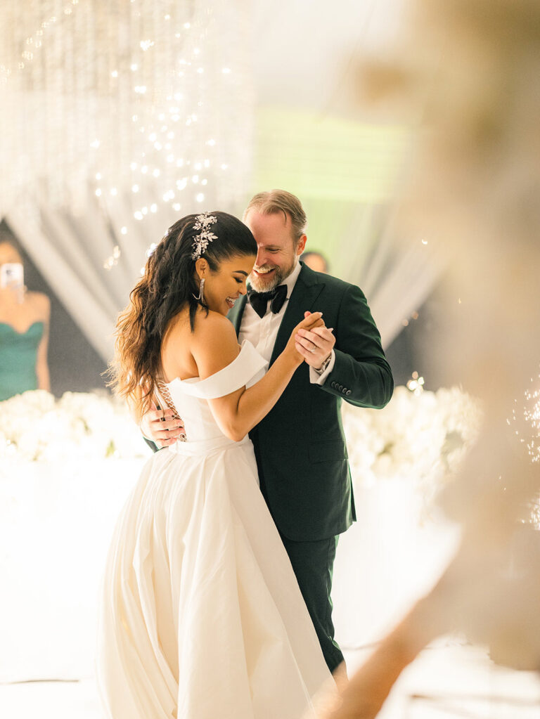 A couple dancing, framed by soft white flowers in the foreground, Tai Flora Luxe