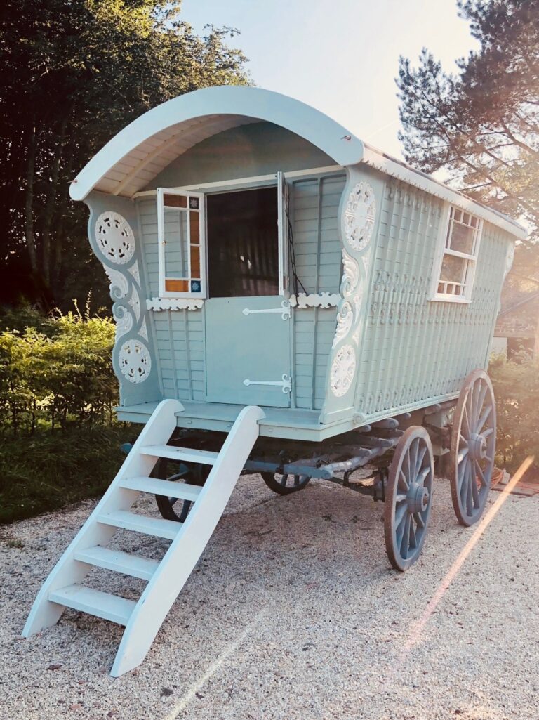 A pale blue showman wagon with carved panels and a white step ladder in the courtyard, Tan House Newland