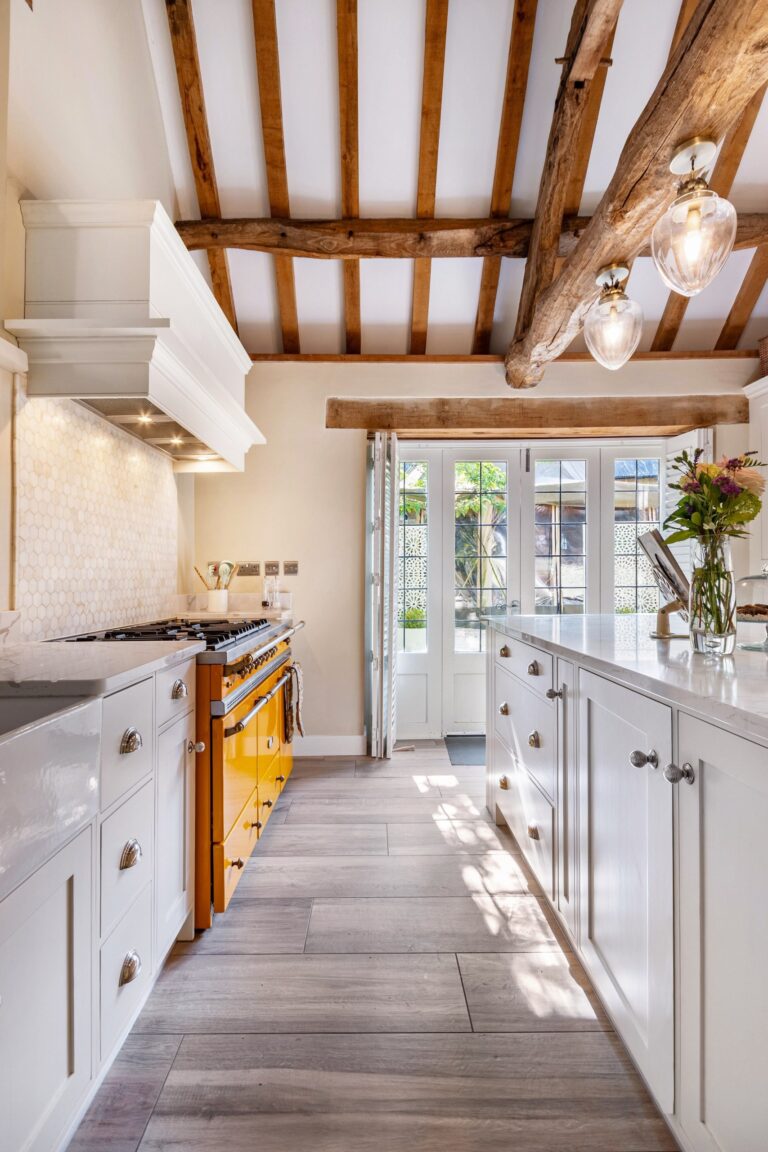 The beamed kitchen in the Wilderness Retreat, with a yellow range cooker and French doors to the garden, Tan House Newland