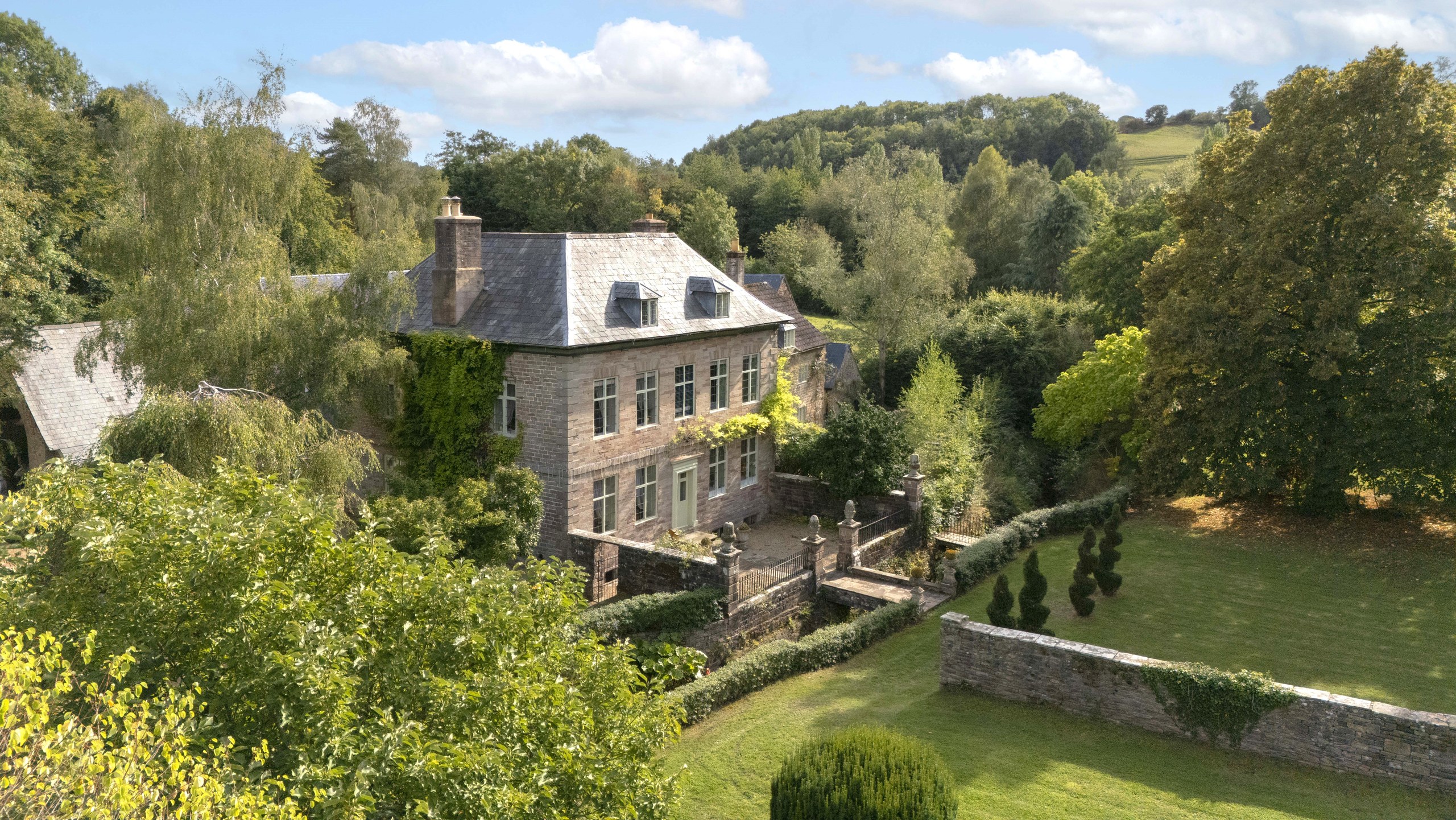 Tan House from above, with its slate roof, terraced garden and lawns set into the wooded Newland valley, Tan House Newland