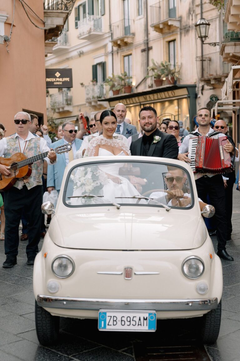 A cream Fiat 500 on the main street with a guitarist and accordionist alongside, Taormina Weddings