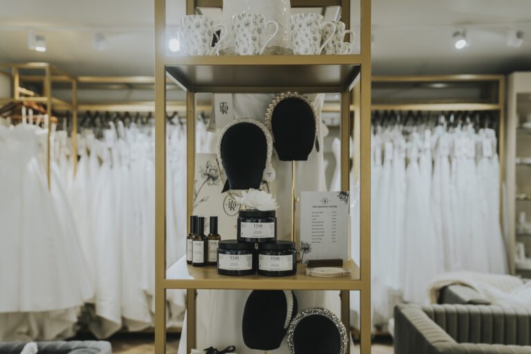 Gold-framed shelving with mannequin heads, candles and rails of gowns, TDR Bridal