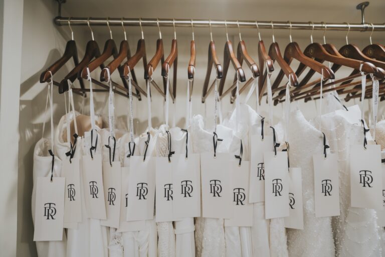 Wedding dresses on wooden hangers with tags, shown in close-up, TDR Bridal