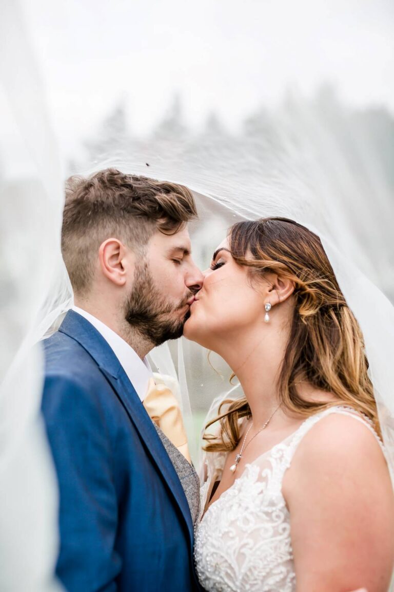 A couple kissing beneath the bride's veil, TDR Bridal