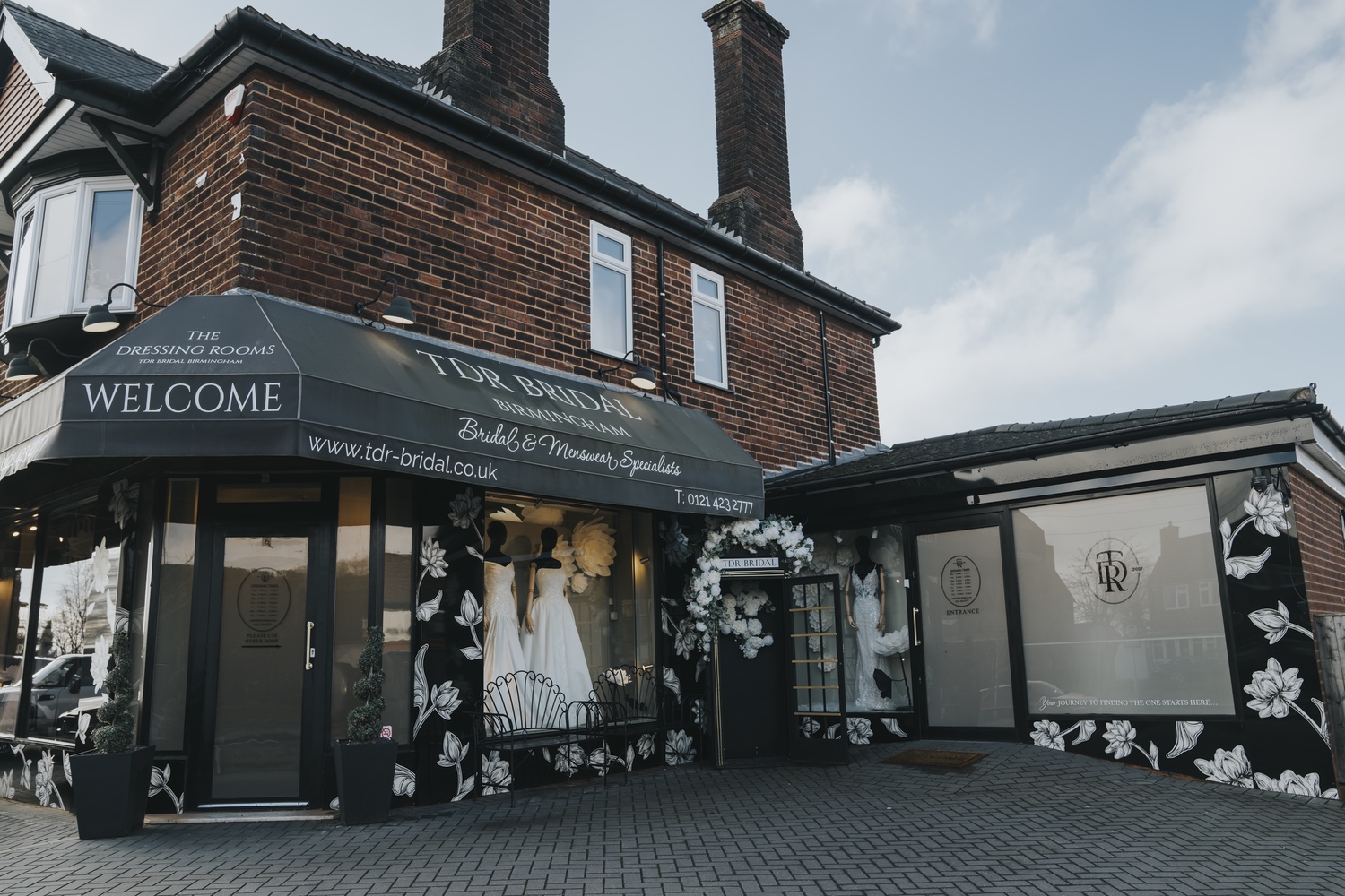 The TDR Bridal boutique on Manor Lane, Halesowen, with its dark awning, floral frontage and a welcome sign, TDR Bridal