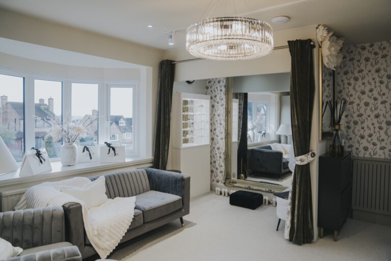 A bridal suite with a bay window, grey sofa, chandelier and mirrored changing area, TDR Bridal