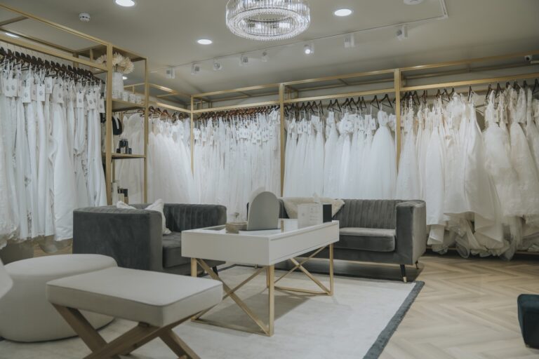 The Adore suite with grey velvet seating, a white table and gowns on gold-framed rails, TDR Bridal