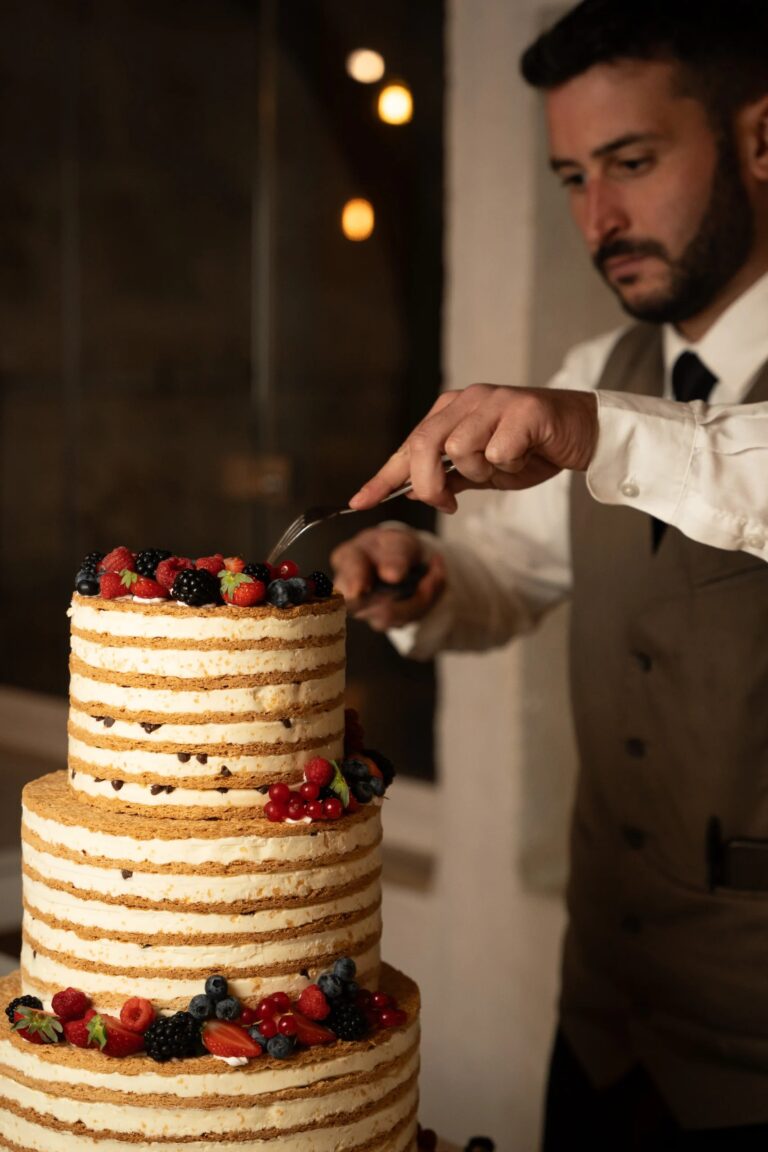 A layered cake with fresh berries being cut at an event, Tenuta Pinto