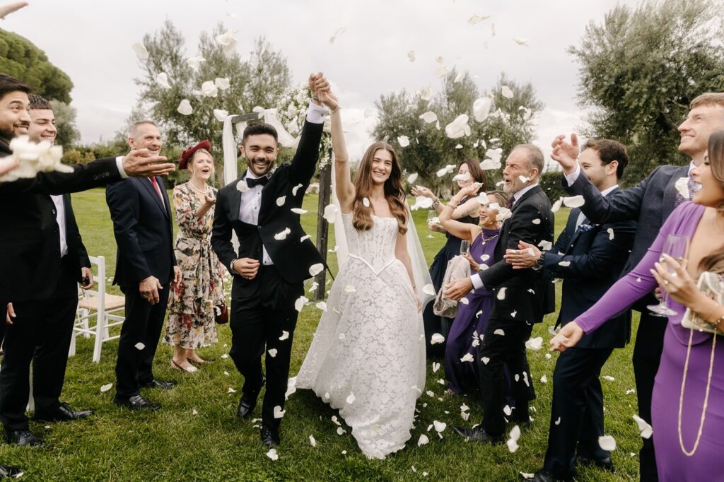 Guests throw petals around the couple on the lawn among the olive trees, Tenuta Pinto