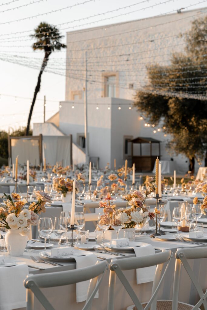 Tables laid with flowers and candles in front of the white masseria, Tenuta Pinto