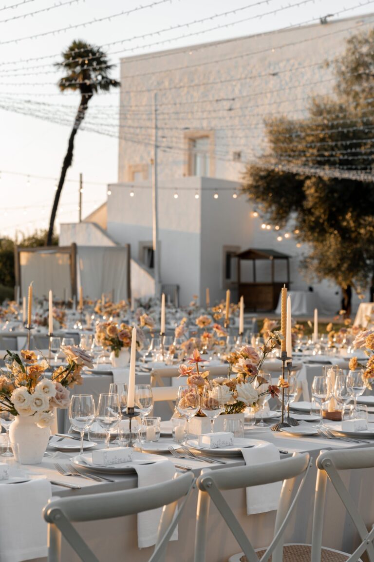 Tables laid with flowers and candles in front of the white masseria, Tenuta Pinto