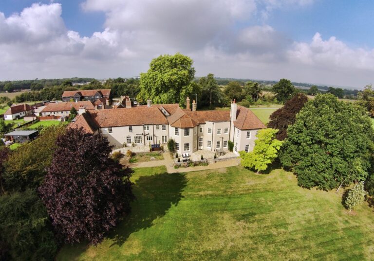 Aerial view over the rear lawn to the house, with farmland and the edge of Churchgate Street beyond, That Amazing Place