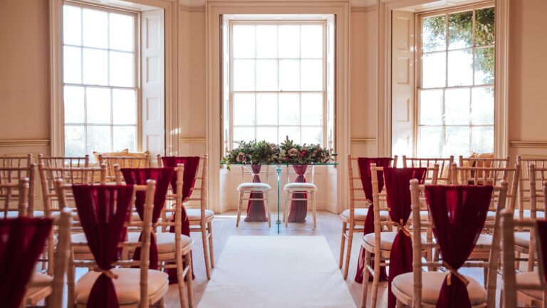 The Lakeview Lounge set for a ceremony, with burgundy chair sashes beneath tall sash windows, That Amazing Place