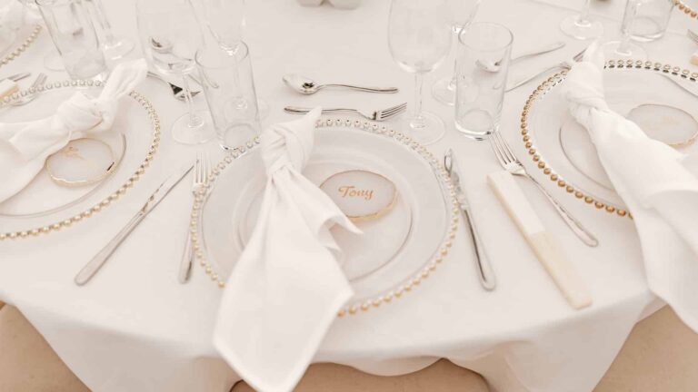 Place settings with gold beaded chargers, folded napkins and name cards, That Amazing Place