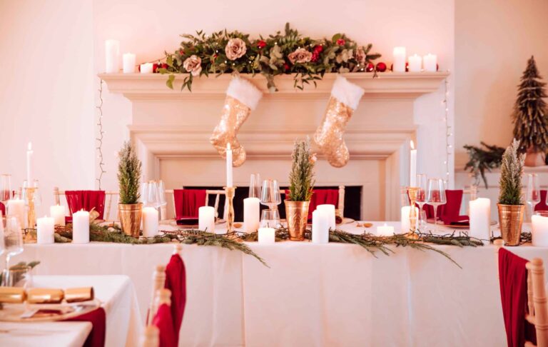 A top table dressed for a Christmas wedding in front of a garlanded fireplace with stockings, That Amazing Place
