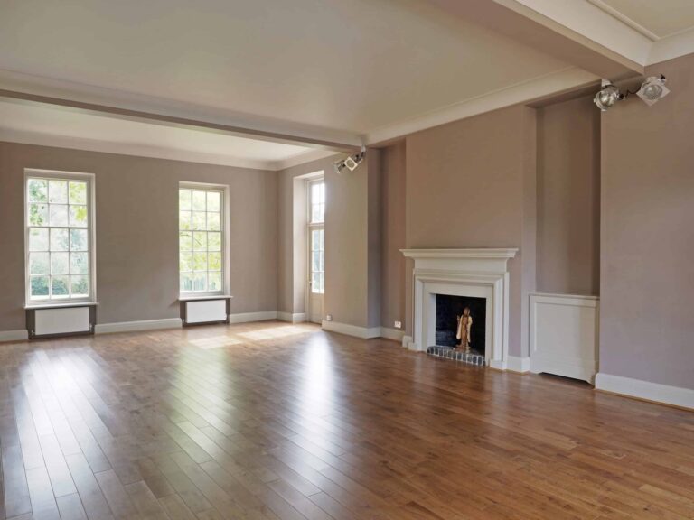 The Hall empty, showing the wooden floor, sash windows and original fireplace, That Amazing Place
